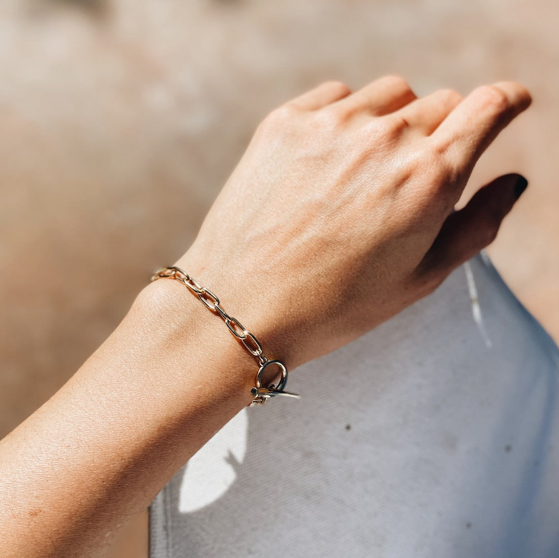 A girl showcasing a baby rectangular chain bracelet in gold vermeil with a stylish tusk clasp on her hand - Gabriela Artigas