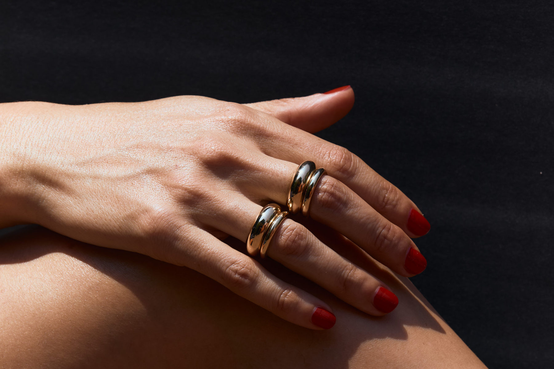 Close-up of a hand with gold rings on a dark background